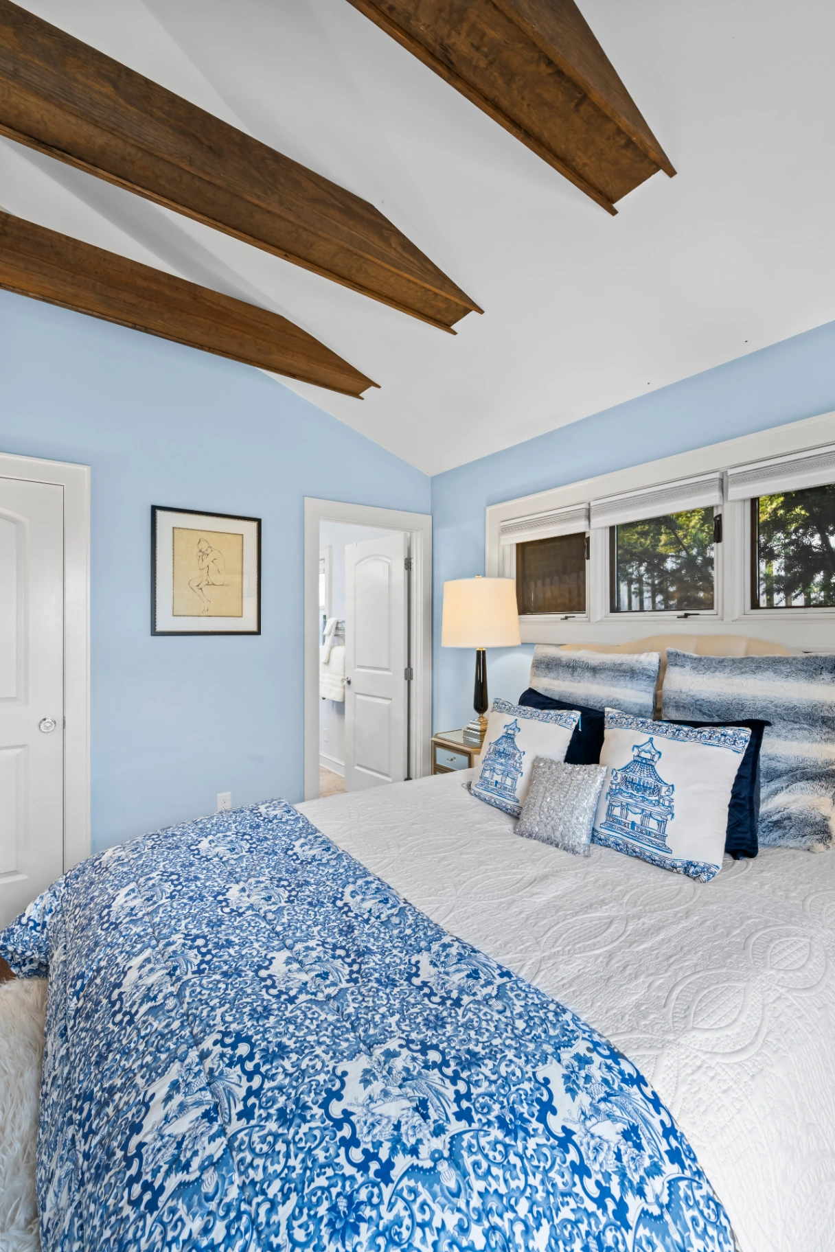Blue bedroom with exposed wood beams and patterned bedding — Asheville vacation rental guest room