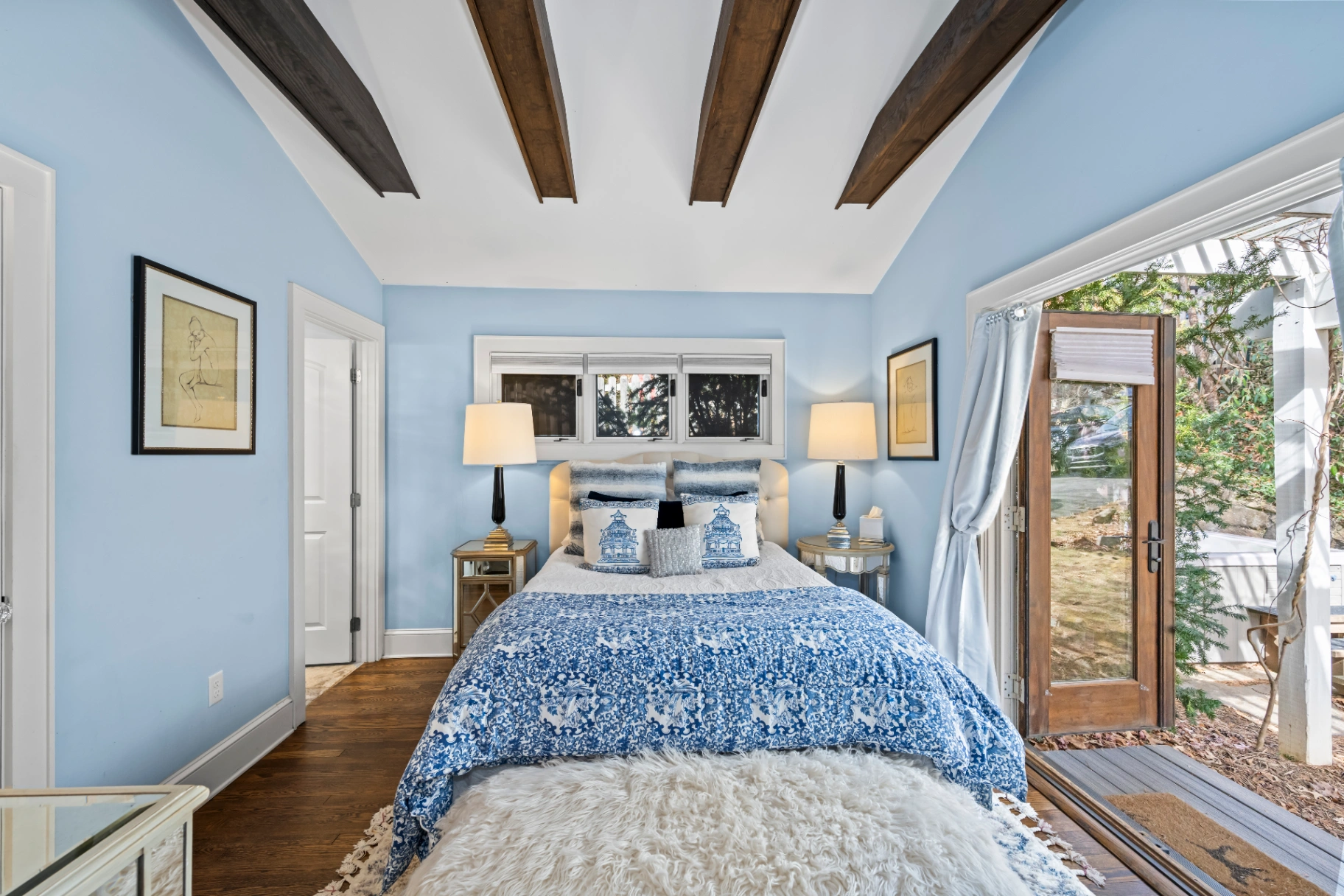 Blue bedroom with exposed wooden ceiling beams and patio door to deck — Asheville NC rental