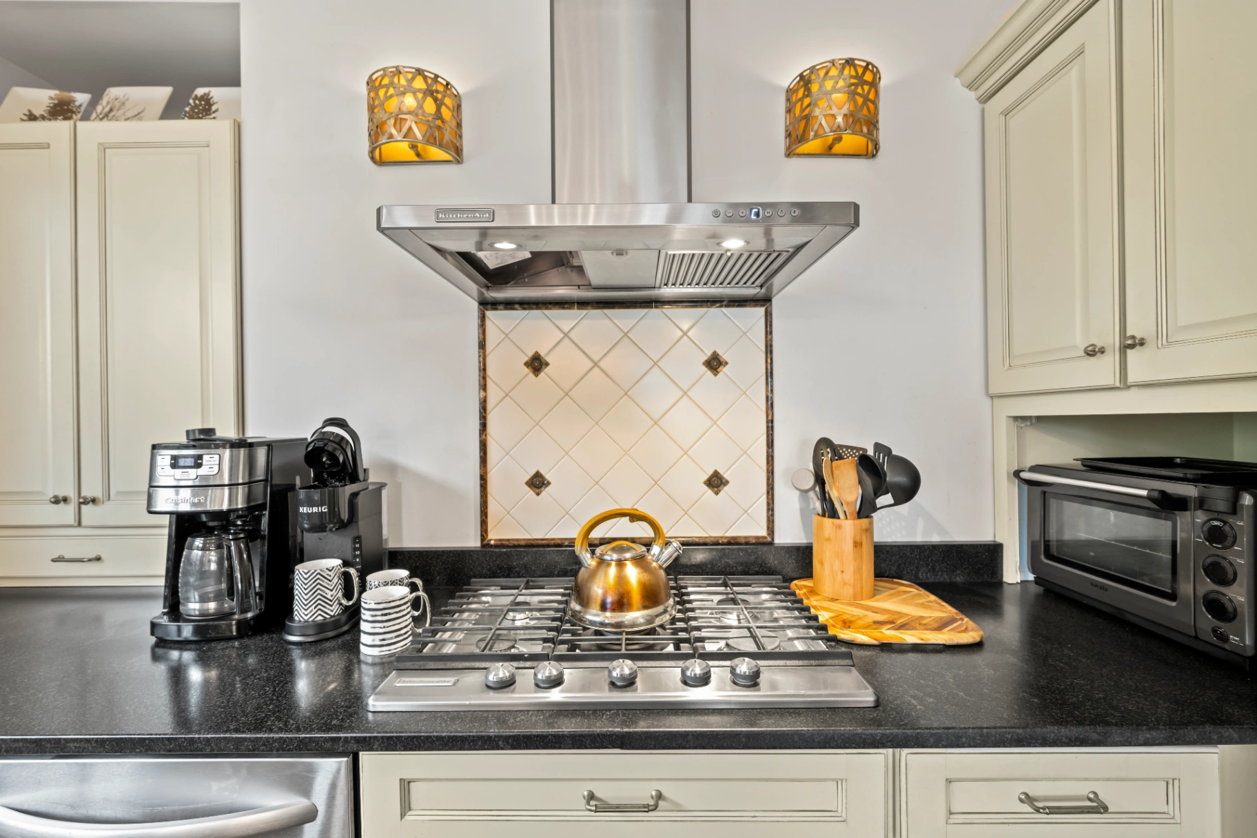 Traditional kitchen with stovetop range hood and black countertop — Asheville vacation rental cooking amenities