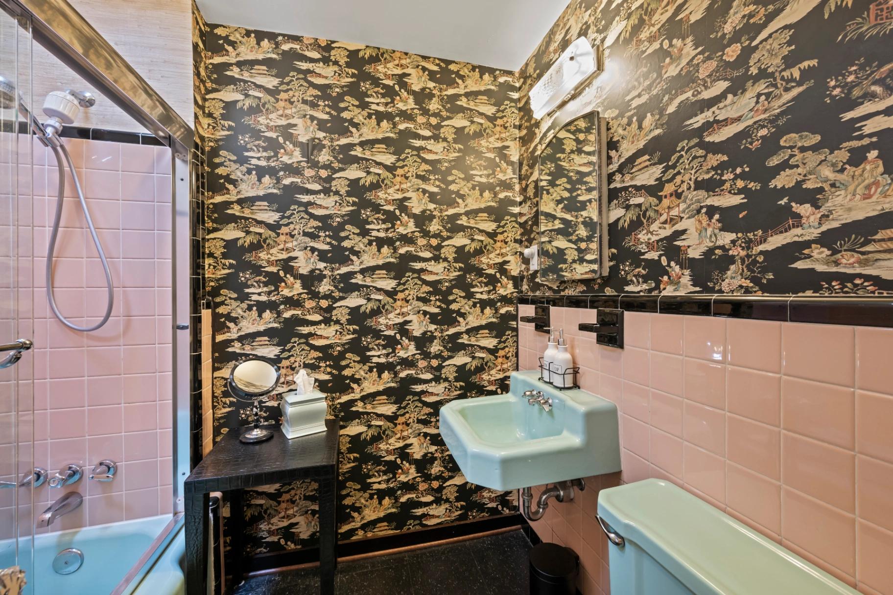 Vintage bathroom with pink tile, teal fixtures, and oriental wallpaper — eclectic mid-century Asheville rental